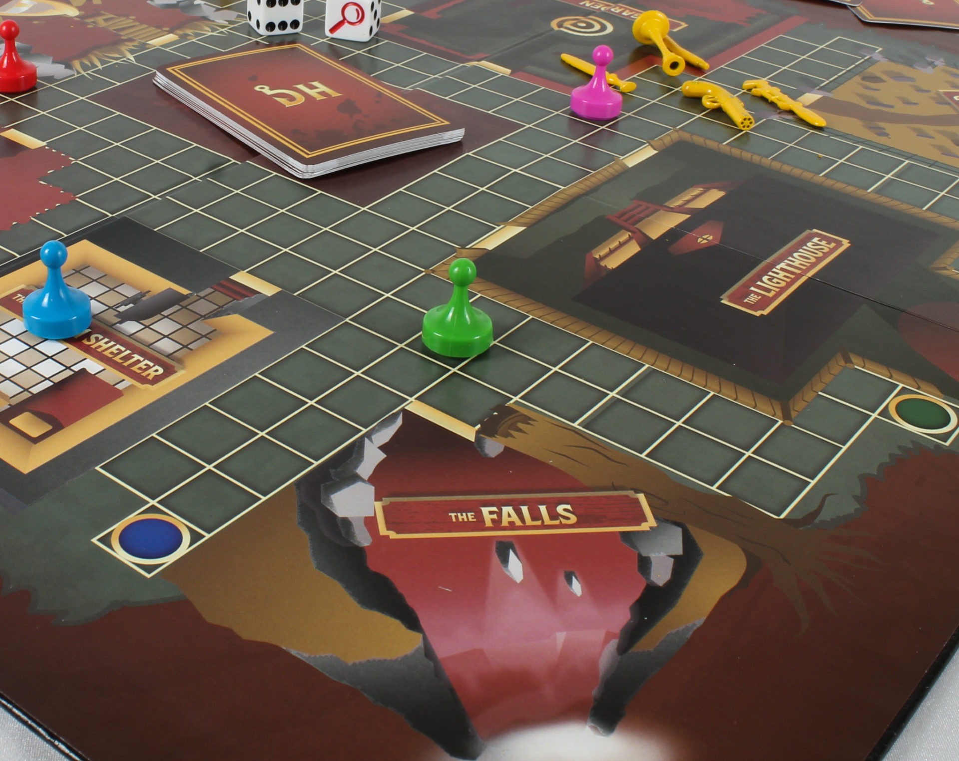 A photo of a close up shot of the corner of a board game called Dead Herrings. You can see three areas on the board including "The Falls", "The Lighthouse", and "The Storm Shelter", along with various board game pieces and cards similiar to that of the board game CLUE.